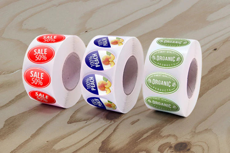 Three rolls of stickers on a brown surface, including sale labels.